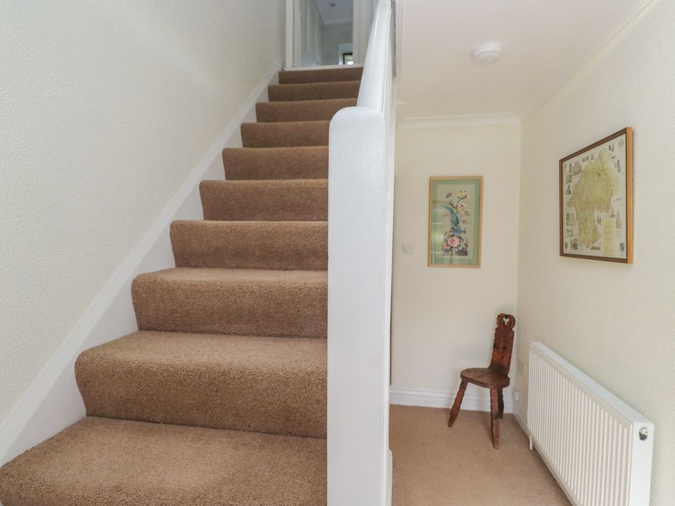 A hallway with stairs and a chair at Throstlegarth in Milnthorpe