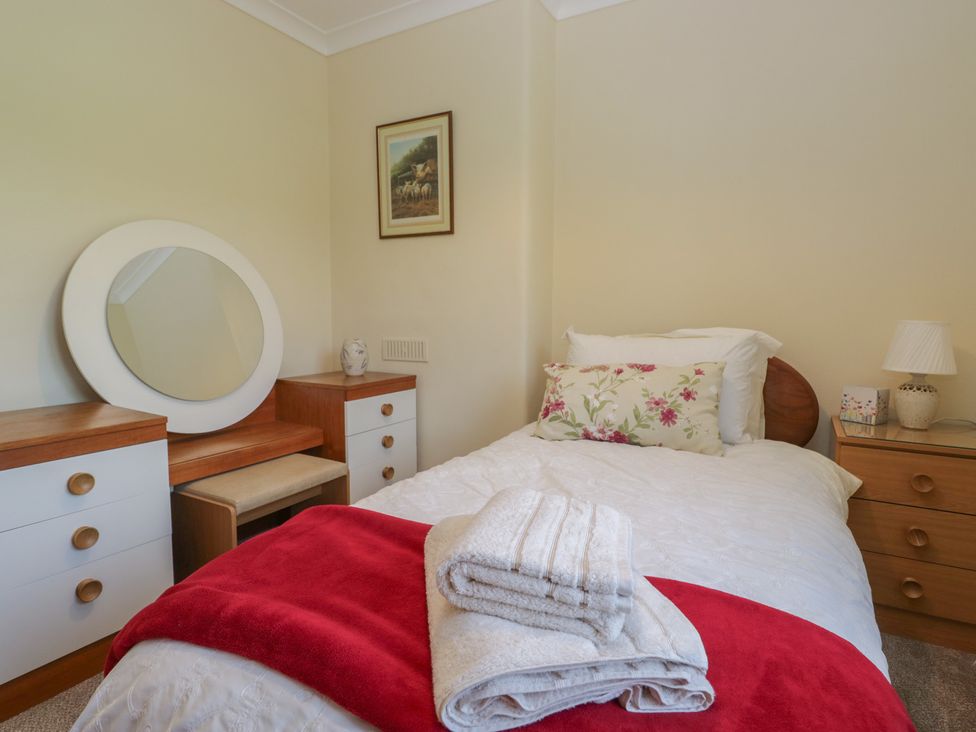 A bedroom with a bed and a mirror at Throstlegarth in Milnthorpe
