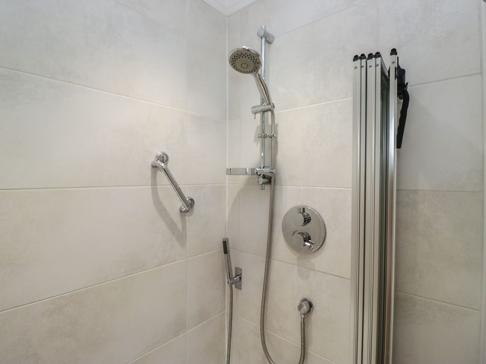A shower with a showerhead and handheld shower in a bathroom at Throstlegarth in Milnthorpe