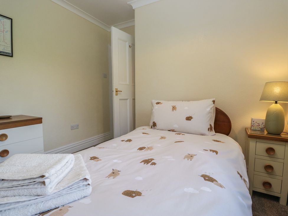 A bedroom with a bed and a nightstand at Throstlegarth in Milnthorpe