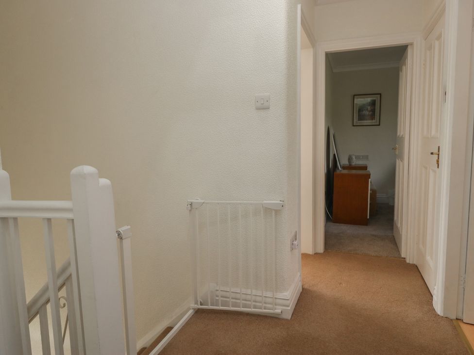 A hallway with a staircase and a safety gate at Throstlegarth in Milnthorpe
