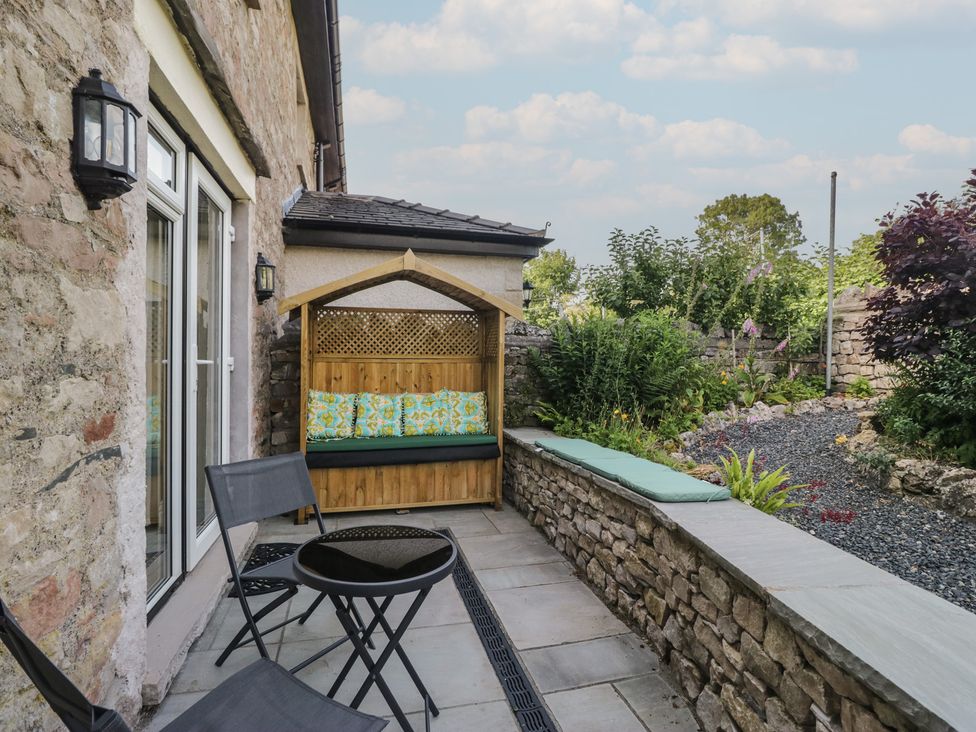An outdoor seating area with a bench and table at Throstlegarth in Milnthorpe