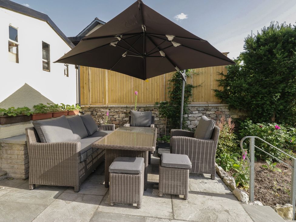 A garden with outdoor furniture and an umbrella at Throstlegarth in Milnthorpe