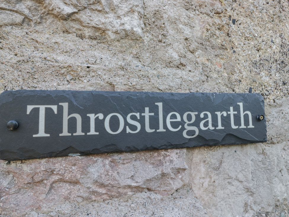 A sign with the name Throstlegarth on a stone wall