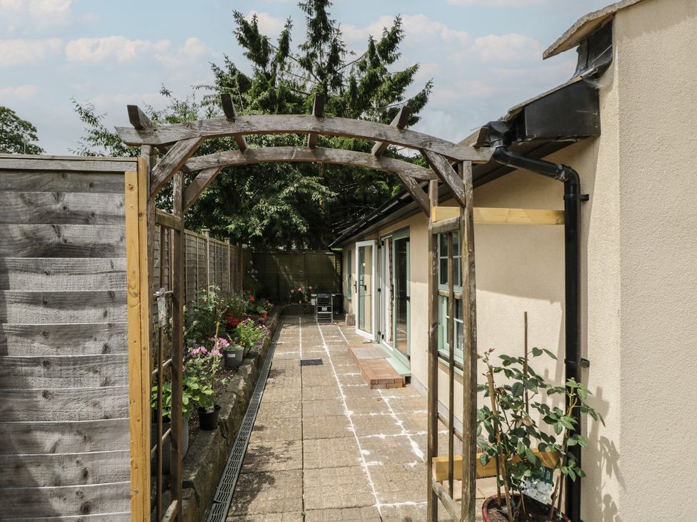 An outdoor pathway with an archway and flower pots at Cosy Cottage in Babbacombe