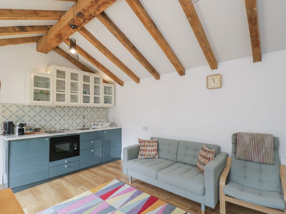 A living room with kitchen unit and sofa at Cosy Cottage in Babbacombe