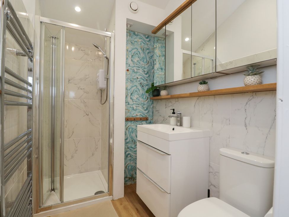 A bathroom featuring a shower, toilet, and sink at Cosy Cottage in Babbacombe