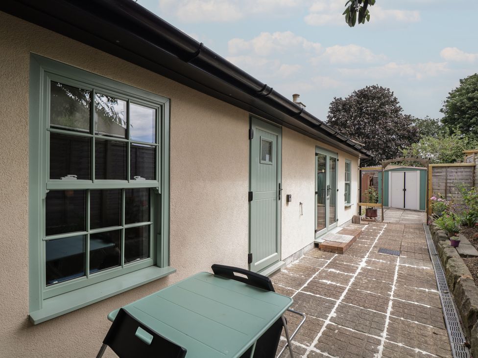 A garden area with a table and windows at Cosy Cottage, Babbacombe