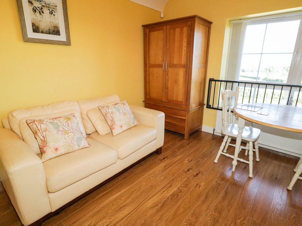 A living room with a sofa, table, and chairs at The Mummers Studio Apartment 1 in Derrylin, County Fermanagh