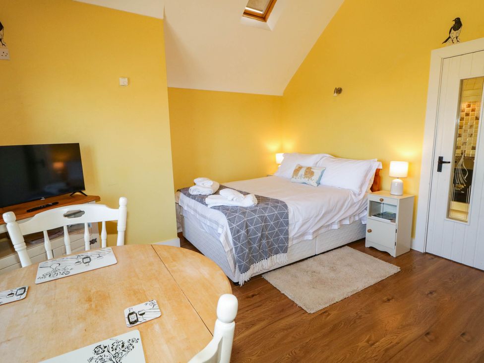 A bedroom with a bed, table, and television at The Mummers Studio Apartment 1, Derrylin, County Fermanagh