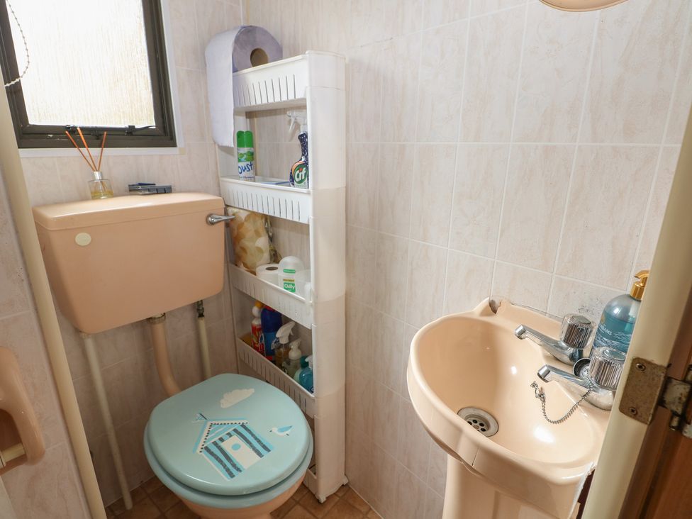 A bathroom with a toilet, sink, and storage shelf at 10 Cater Gardens in Guildford