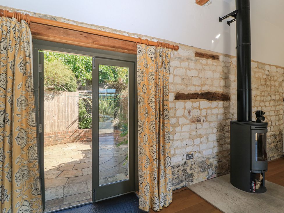 A living room with a wood stove and double doors at Frome Gazey in Frampton