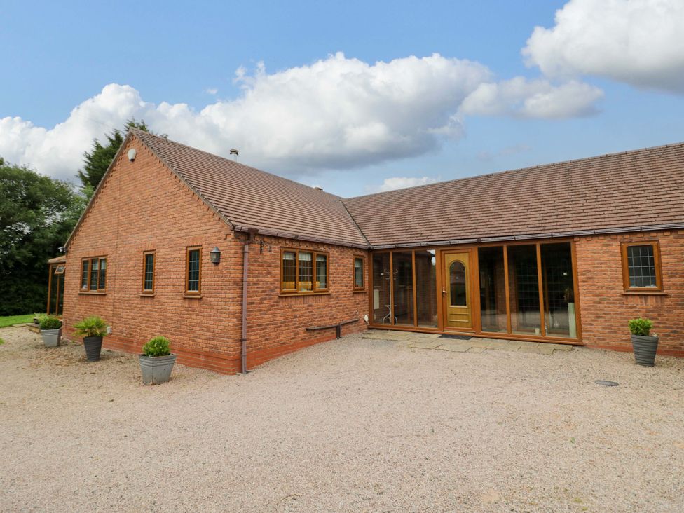 A brick house with gravel area and planters at Meadow View Bungalow in Droitwich