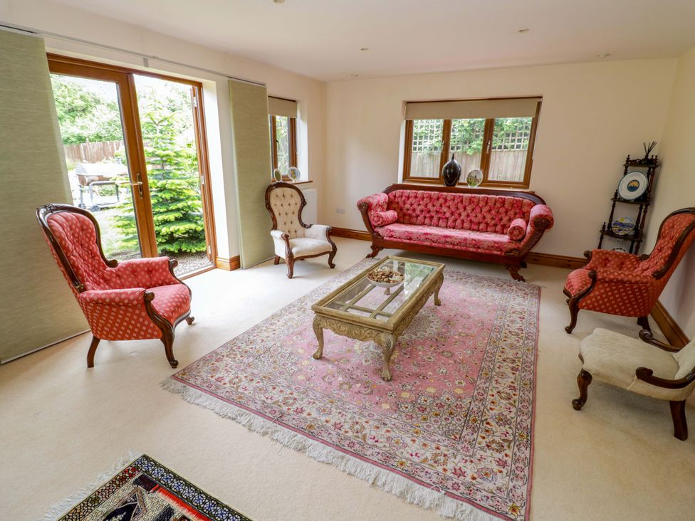 A living room with a pink sofa and chairs at Meadow View Bungalow in Droitwich