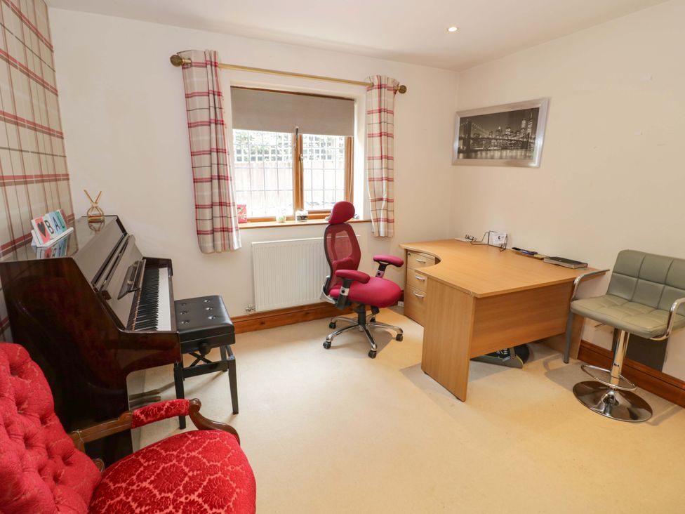 A home office with a desk and piano at Meadow View Bungalow in Droitwich