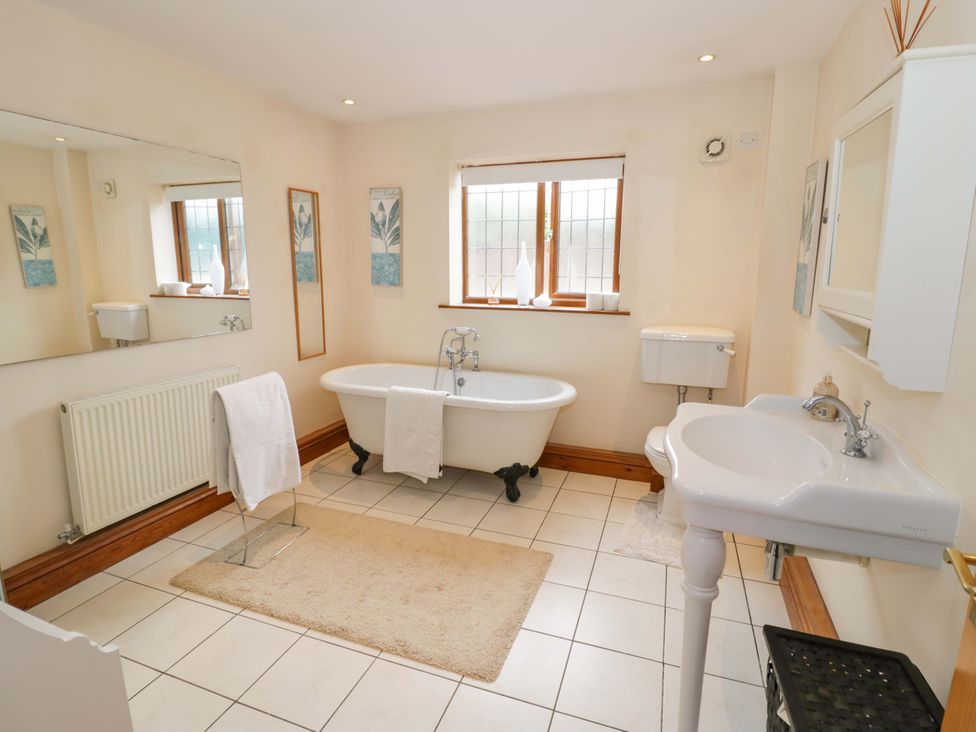A bathroom with a bathtub, toilet, sink, and radiator at Meadow View Bungalow in Droitwich
