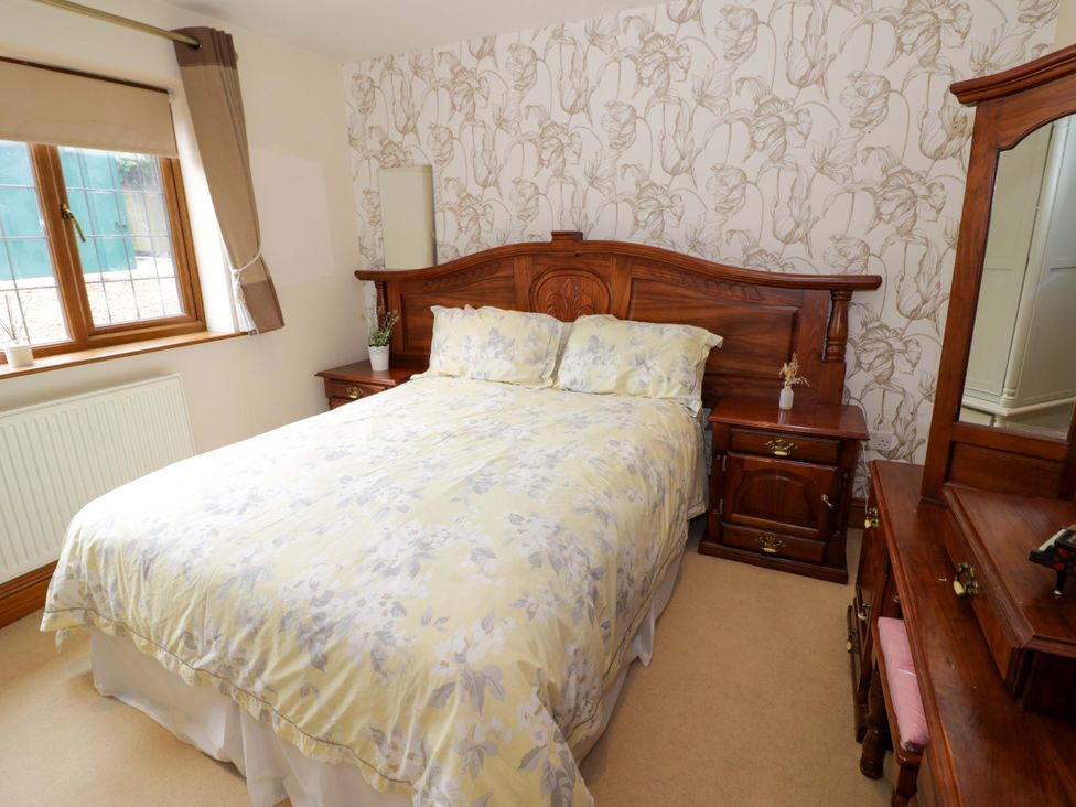 A bedroom with a wooden bed and nightstand at Meadow View Bungalow in Droitwich