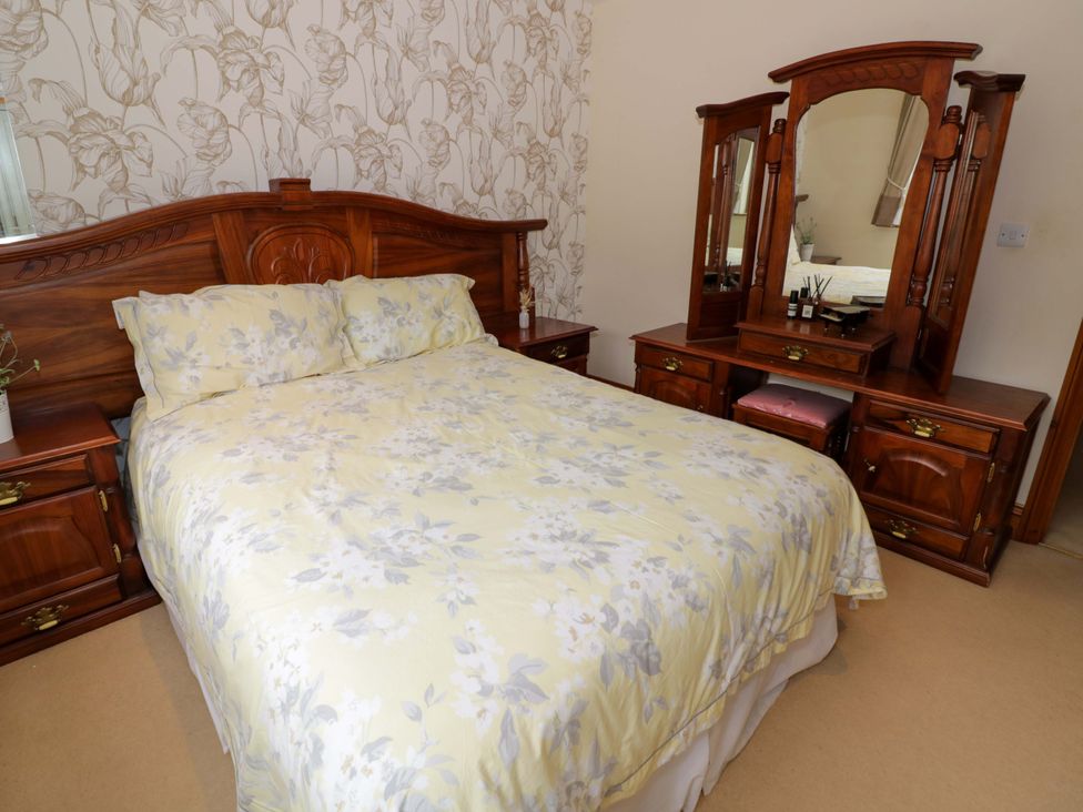 A bedroom with a bed and a dressing table at Meadow View Bungalow in Droitwich