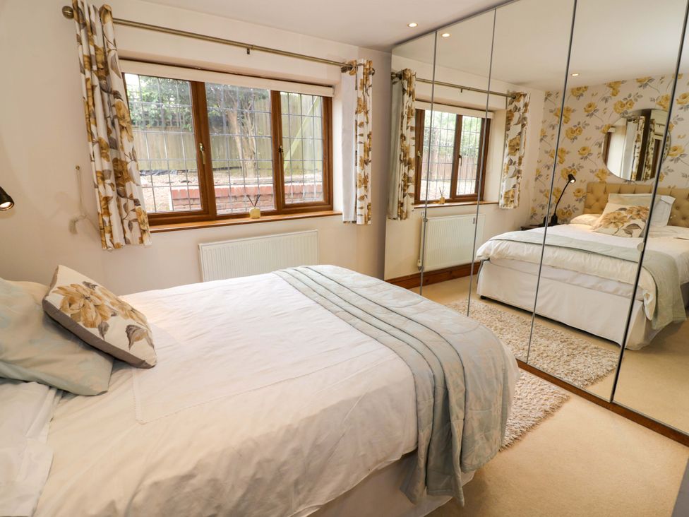 A bedroom layout with a bed and a mirrored wardrobe at Meadow View Bungalow Droitwich