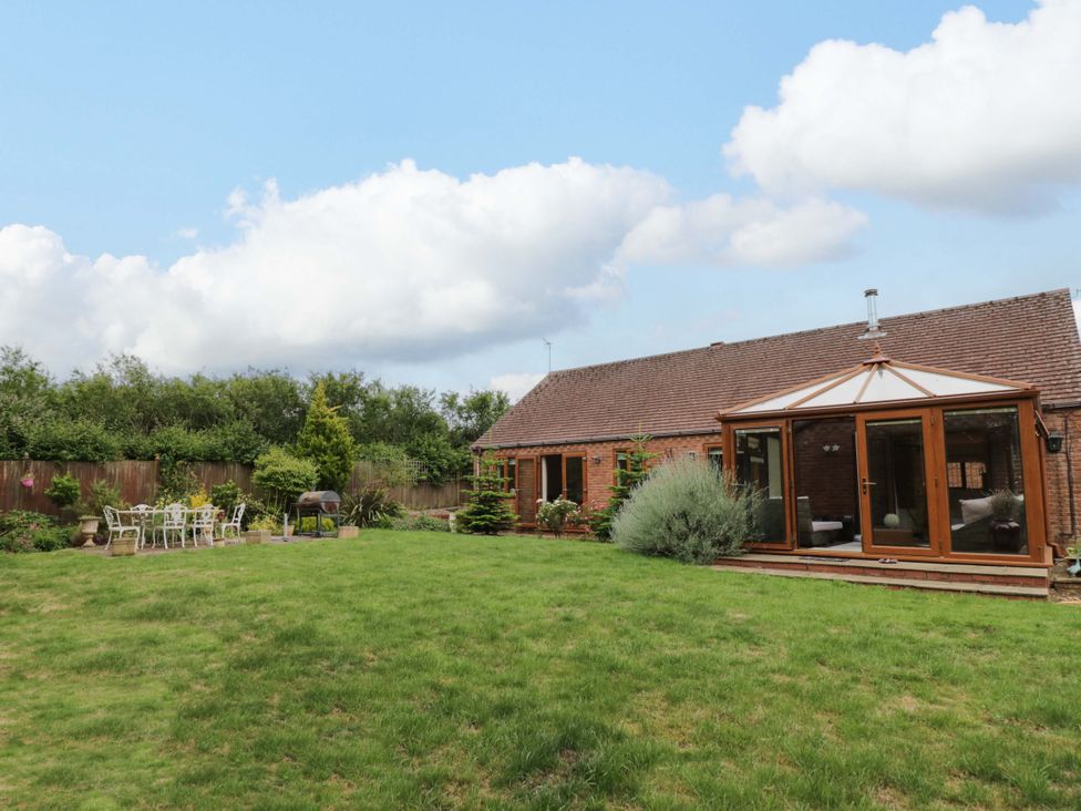 A garden with a bungalow and patio furniture at Meadow View Bungalow in Droitwich