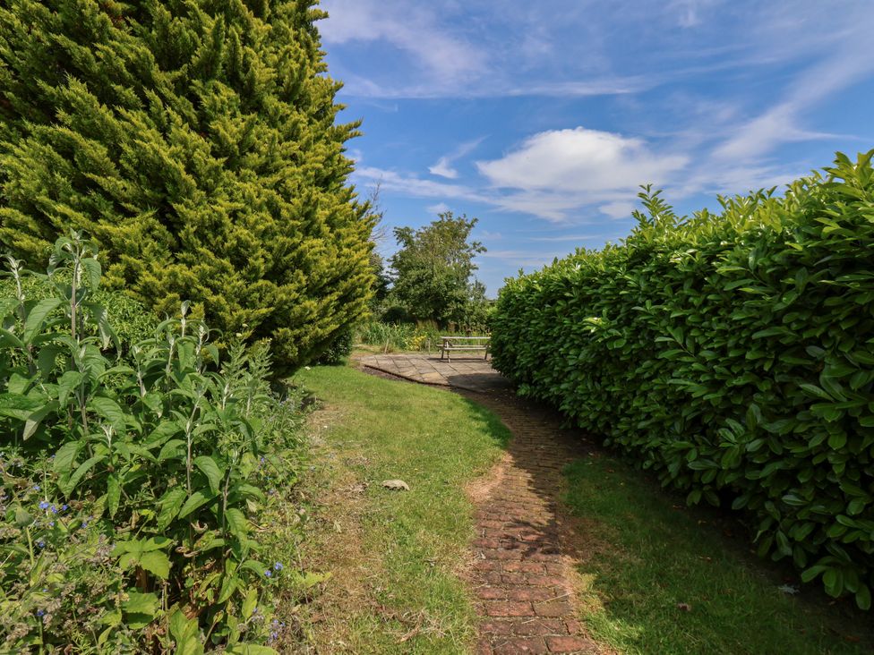 A pathway with hedges and a table in the garden at Granary in Pickering