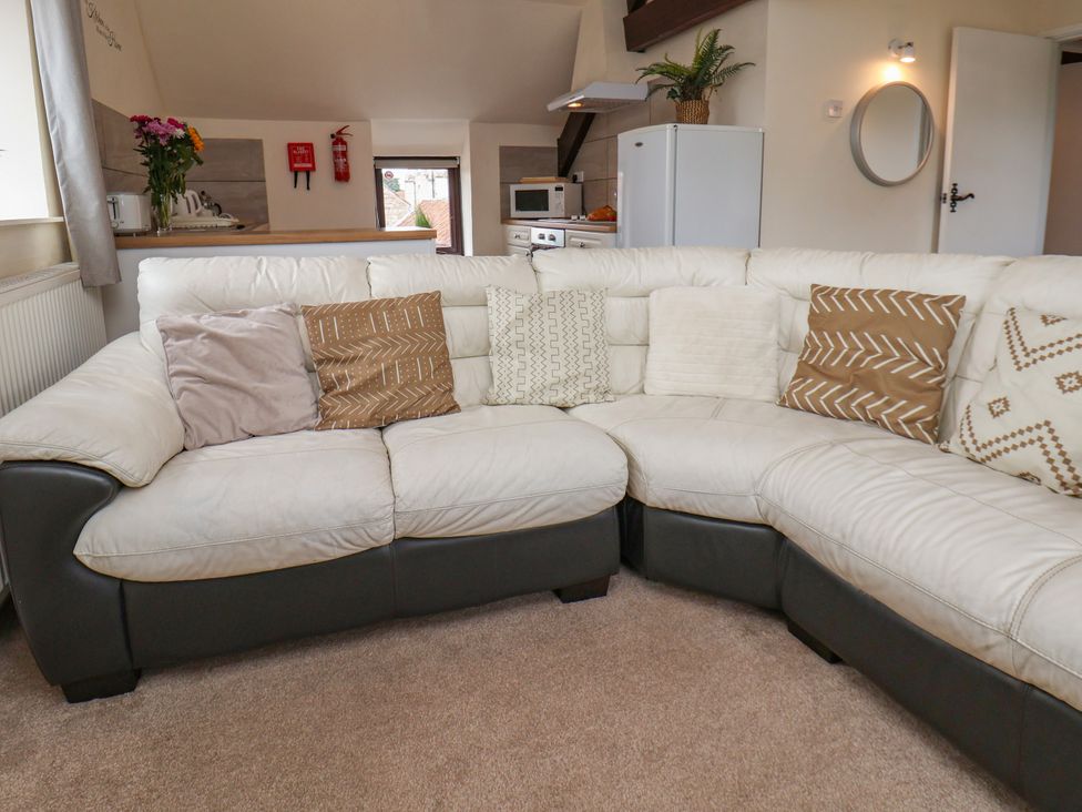 A living room with a sectional sofa and kitchen appliances at Granary in peterculter