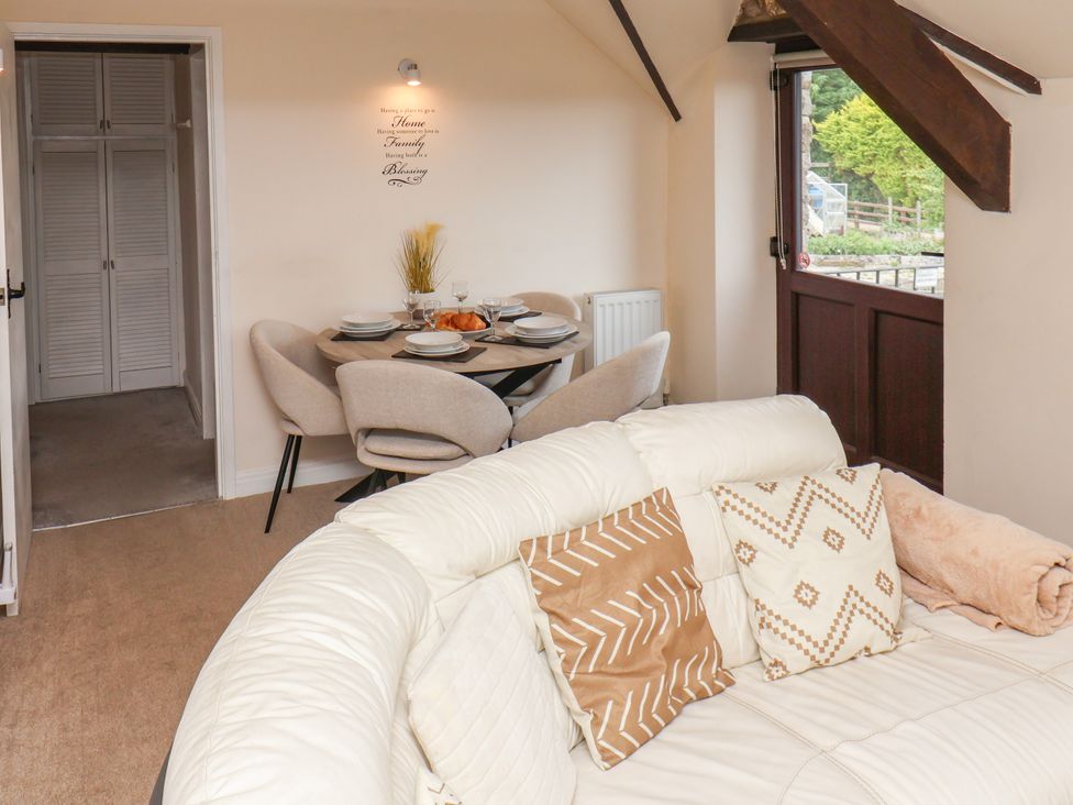 A living room with a dining area and open door at Granary in peterculter