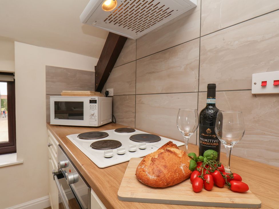 A kitchen with a microwave and wine bottles at Granary in peterculter
