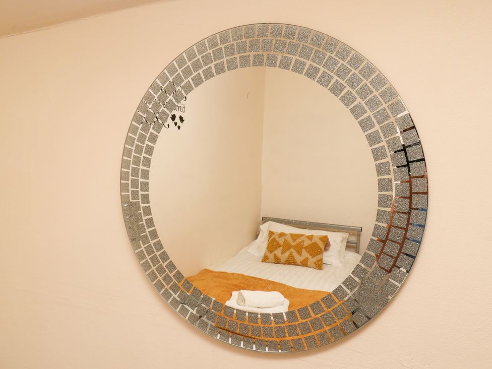 A mirror reflecting a bed with a pillow and blanket at Granary in peterculter