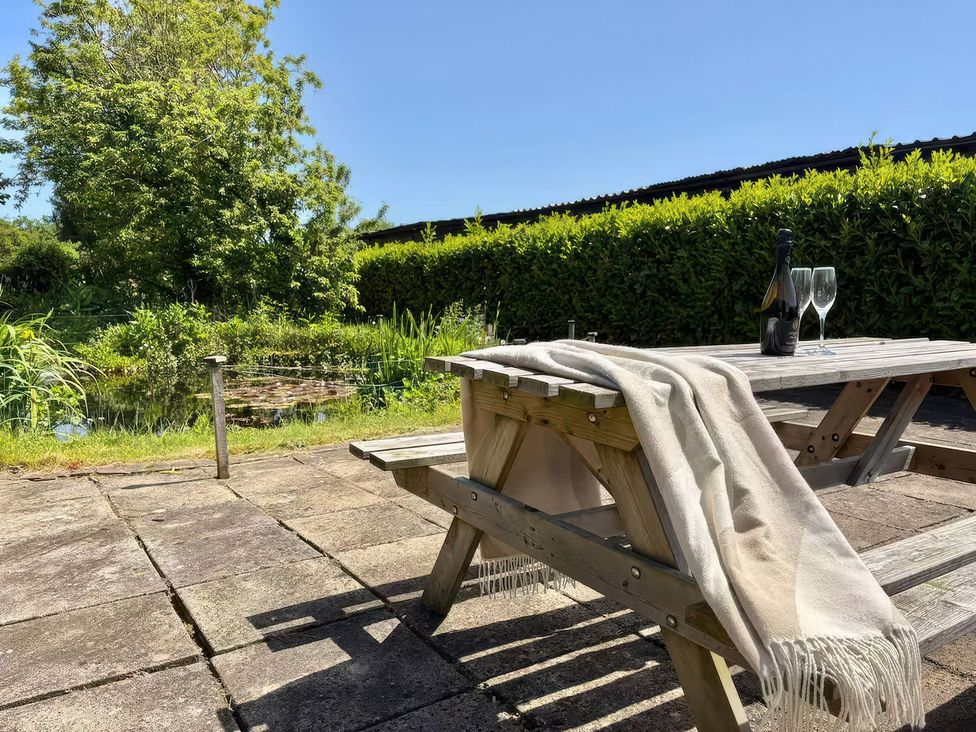 A table with a blanket and a wine bottle with glasses in the garden at Granary in peterculter