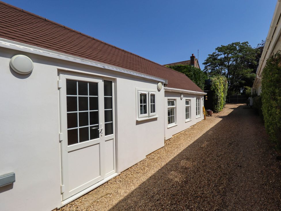 An outdoor area with a gravel path and a building with windows at Bee Hive Hut in Middleton, Norfolk