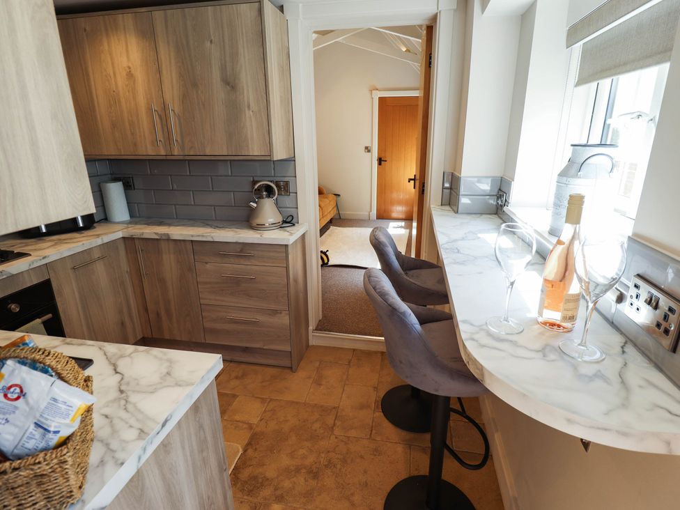 A kitchen with bar stools and wine glasses at Bee Hive Hut in Middleton, Norfolk