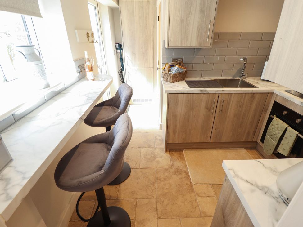 A kitchen with stools and sink at Bee Hive Hut Middleton, Norfolk