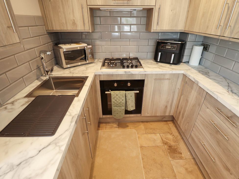A kitchen with a sink, stove, microwave, and countertop at Bee Hive Hut in Middleton, Norfolk