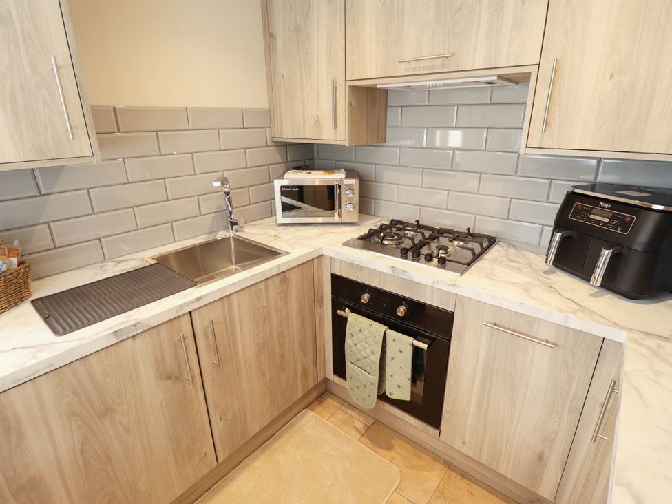 A kitchen with a sink, stove, and microwave at Bee Hive Hut, Middleton, Norfolk