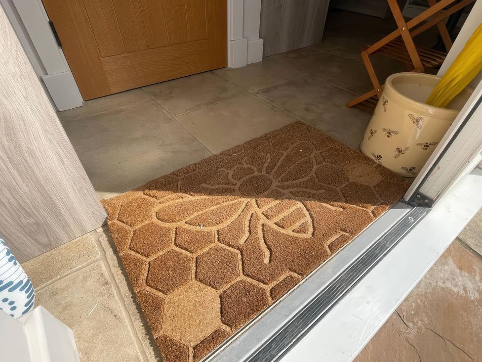 An entryway with a doormat and a pot for items at Bee Hive Hut in Middleton, Norfolk