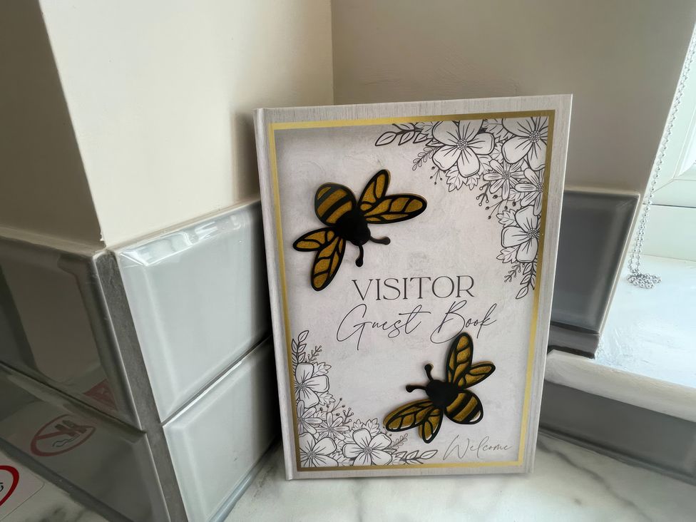 A guest book with floral and bee design at Bee Hive Hut in Middleton, Norfolk