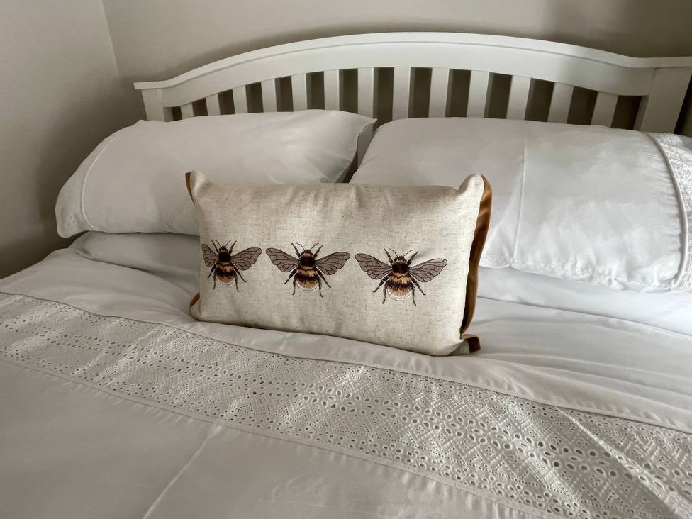 A bed with a bee print cushion and pillows at Bee Hive Hut in Middleton, Norfolk