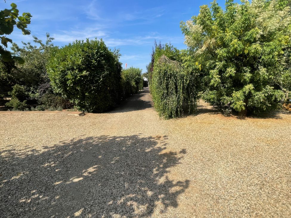 A garden with a gravel path and green shrubs at Bee Hive Hut, Middleton, Norfolk