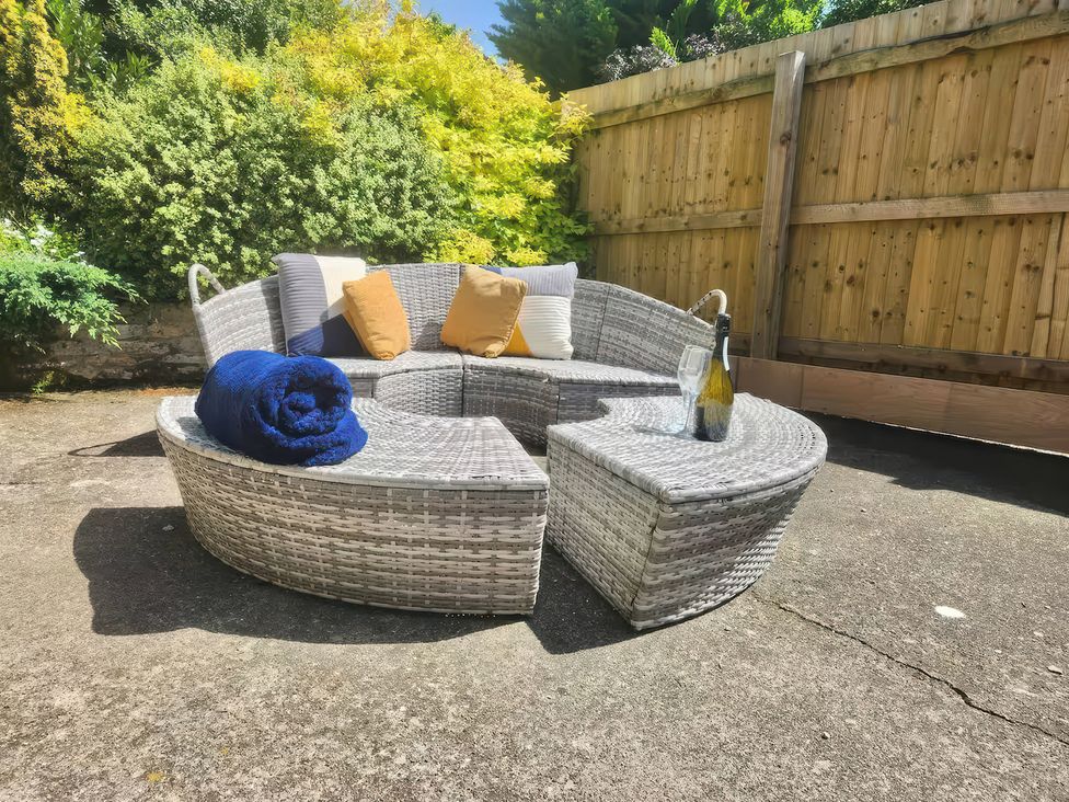An outdoor sofa with cushions and a wine bottle at Owl in Pickering