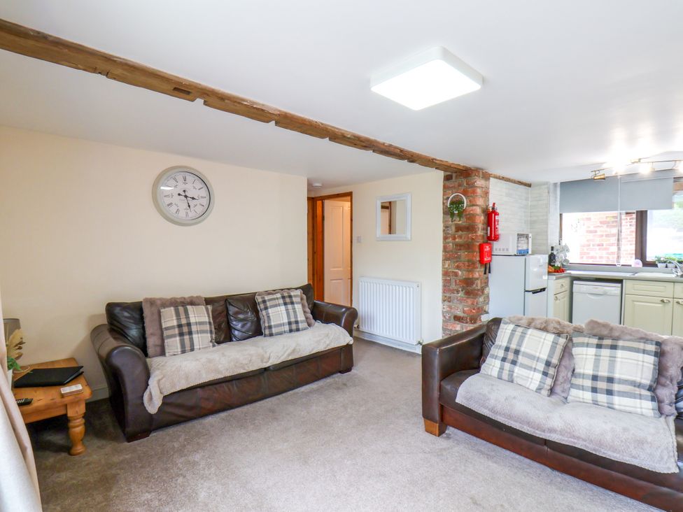 A living room with sofas and a kitchen area at Owl in Pickering