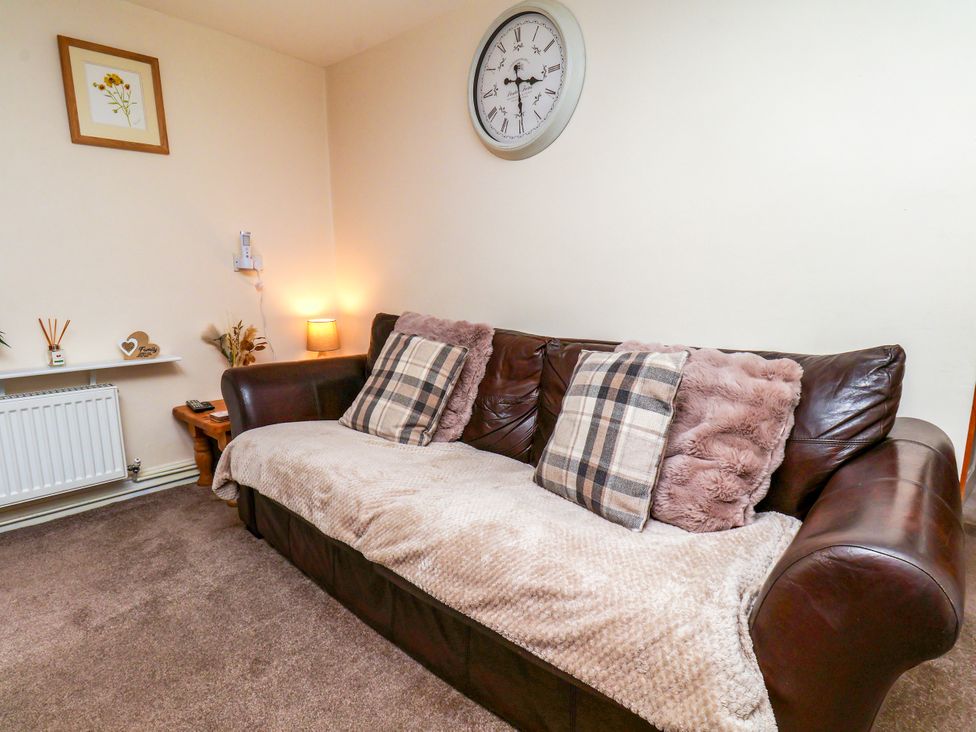 A living room with a sofa and wall clock at Owl in Pickering