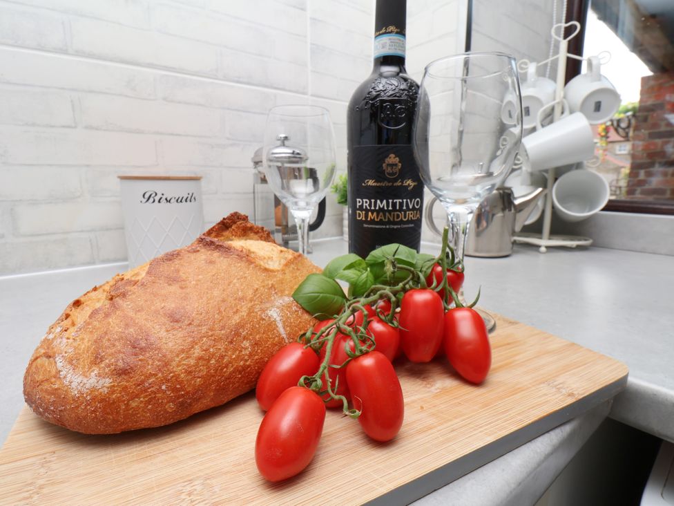 A kitchen scene with bread, wine, glasses and tomatoes at Owl in Pickering