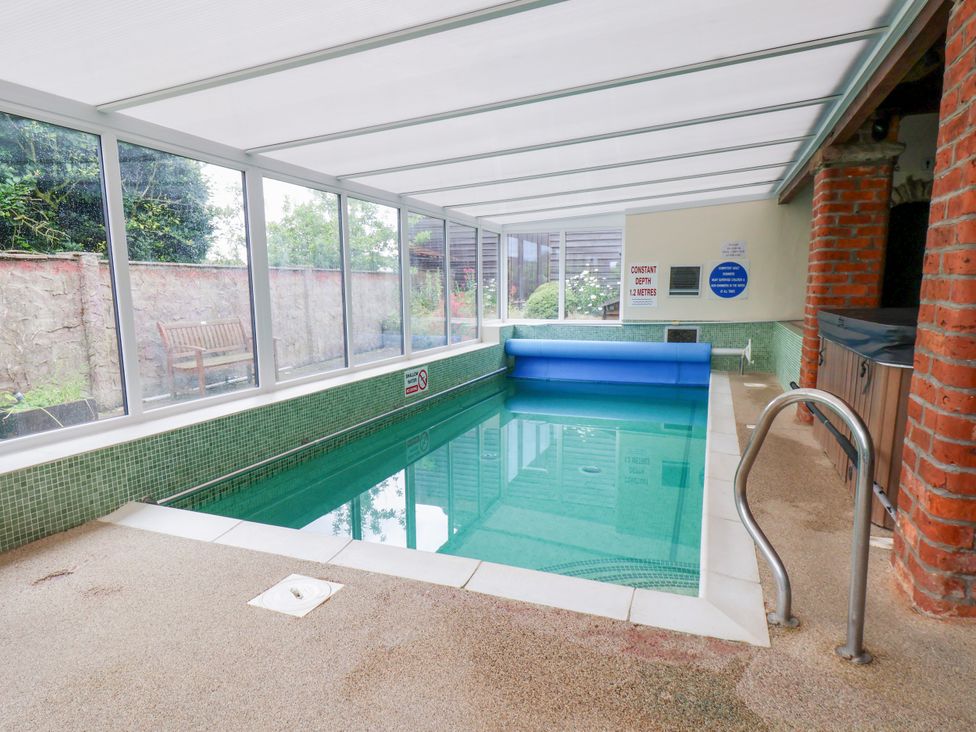 An indoor swimming pool with a pool cover and a hot tub at Owl in Pickering