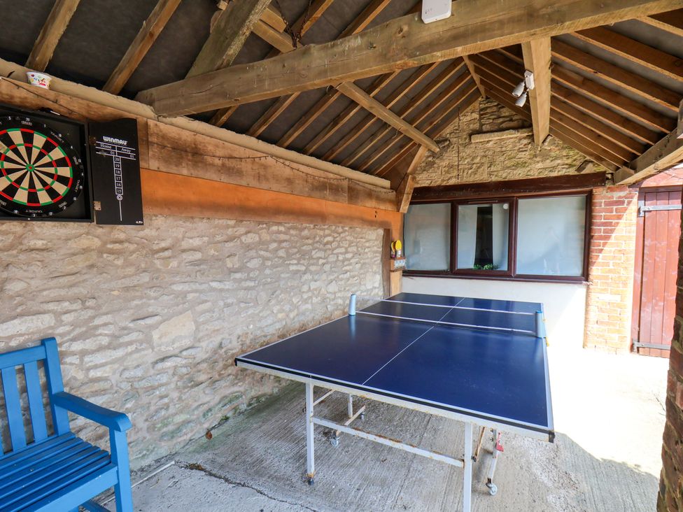 An outdoor games area with a dartboard and ping pong table at Owl in Pickering
