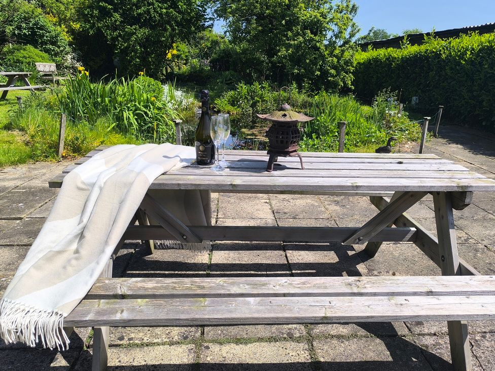 A garden table with a blanket, bottle, and glasses at Owl in Pickering