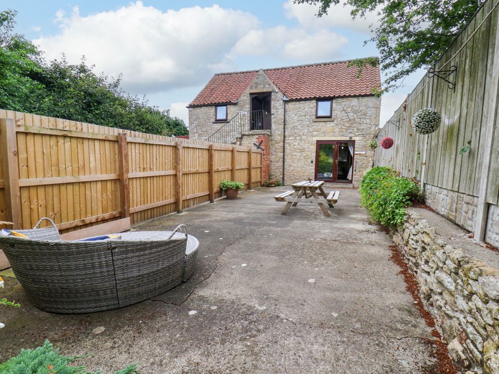A courtyard with a stone building and seating at Owl in Pickering