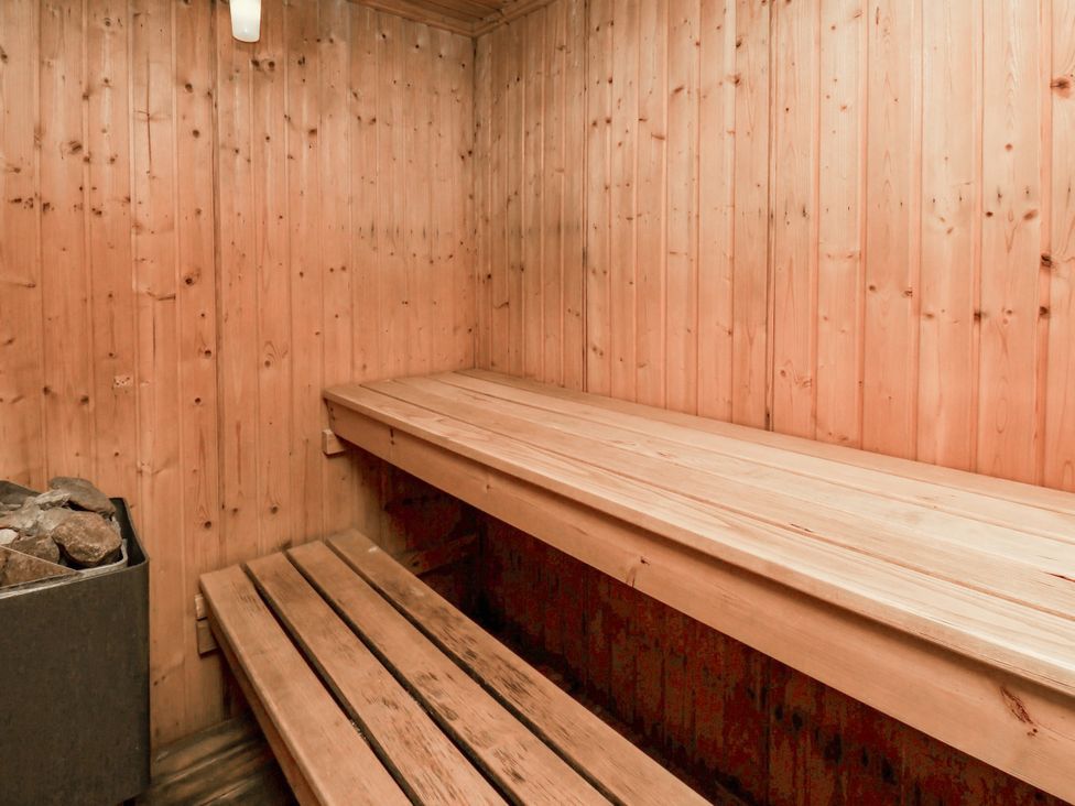 A sauna with wooden benches and a stone stove at Owl in Pickering