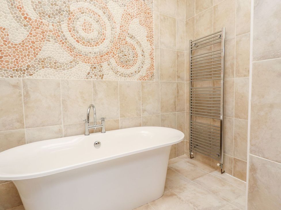 A bathroom with a bathtub and towel radiator at Shepherd's Barn in Lancaster