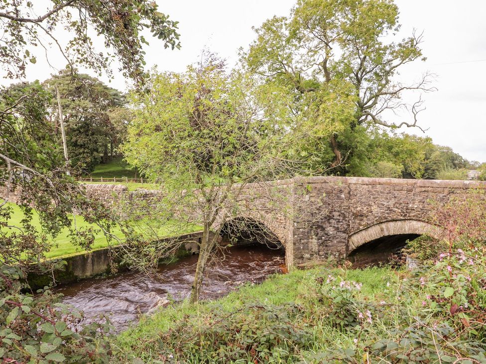 A bridge over a river with trees and grass in the foreground at Shepherd's Barn in Lancaster
